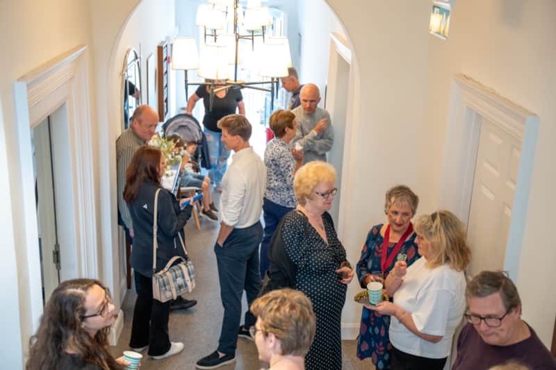 Guests gathered in the hallway under the chandelier at a celebration