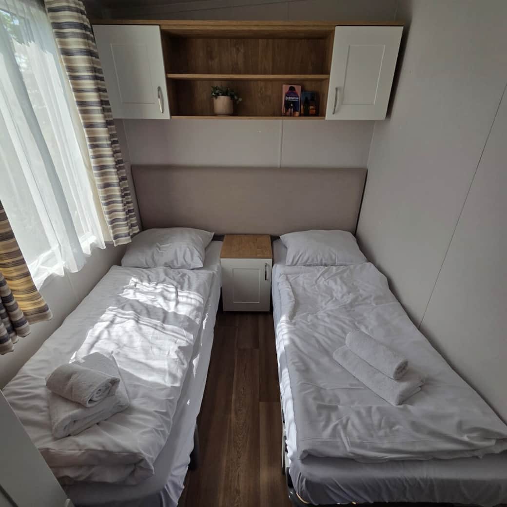 Modernes Schlafzimmer mit zwei Einzelbetten, großem Kleiderschrank und viel natürlichem Licht – perfekt für zwei Personen.