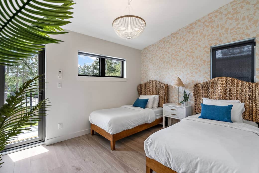 Second bedroom with two twin beds, en suite bathroom, and balcony access. Both windows as well as the door have blinds.