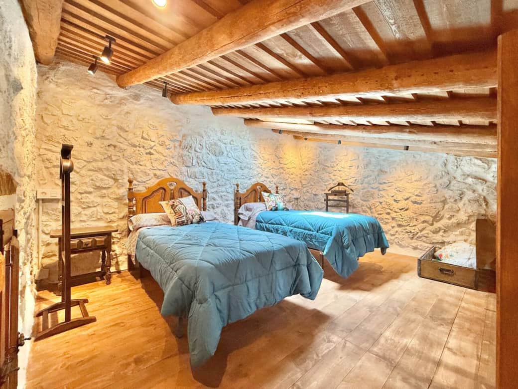 Dormitorio con techo abuhardillado y dos camas individuales, situado en un apartamento independiente junto a la piscina. Cuenta con cocina, salón y baño propio. Ideal para jóvenes o familias que busquen más independencia y un toque de aventura. Dormitorio con techo abuhardillado y dos camas individuales, situado en un apartamento independiente junto a la piscina. Cuenta con cocina, salón y baño propio. Ideal para jóvenes o familias que busquen más independencia y un toque de aventura.