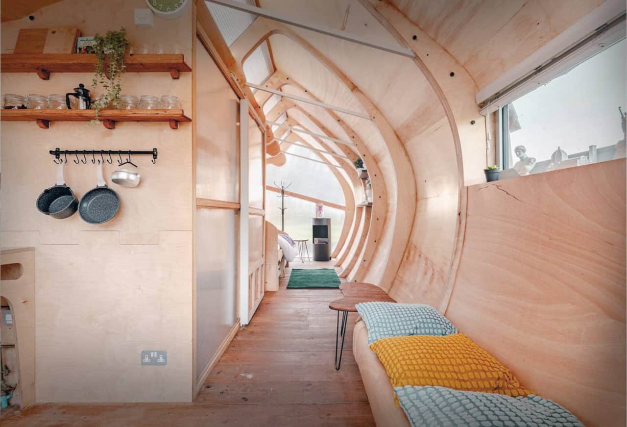 Monocoque Cabin — A single open interior — ribbed plywood walls flow from sleeping to living to cooking and out.