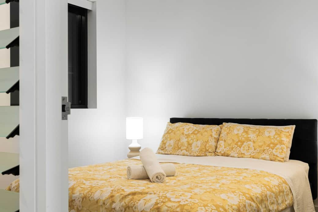 Retreat to our serene bedroom, featuring a plush bed with inviting yellow linens. The soft lighting and tranquil decorations create a peaceful sanctuary for restful nights.