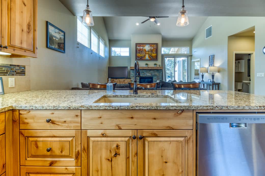 Kitchen peninsula with granite countertops and views into great room