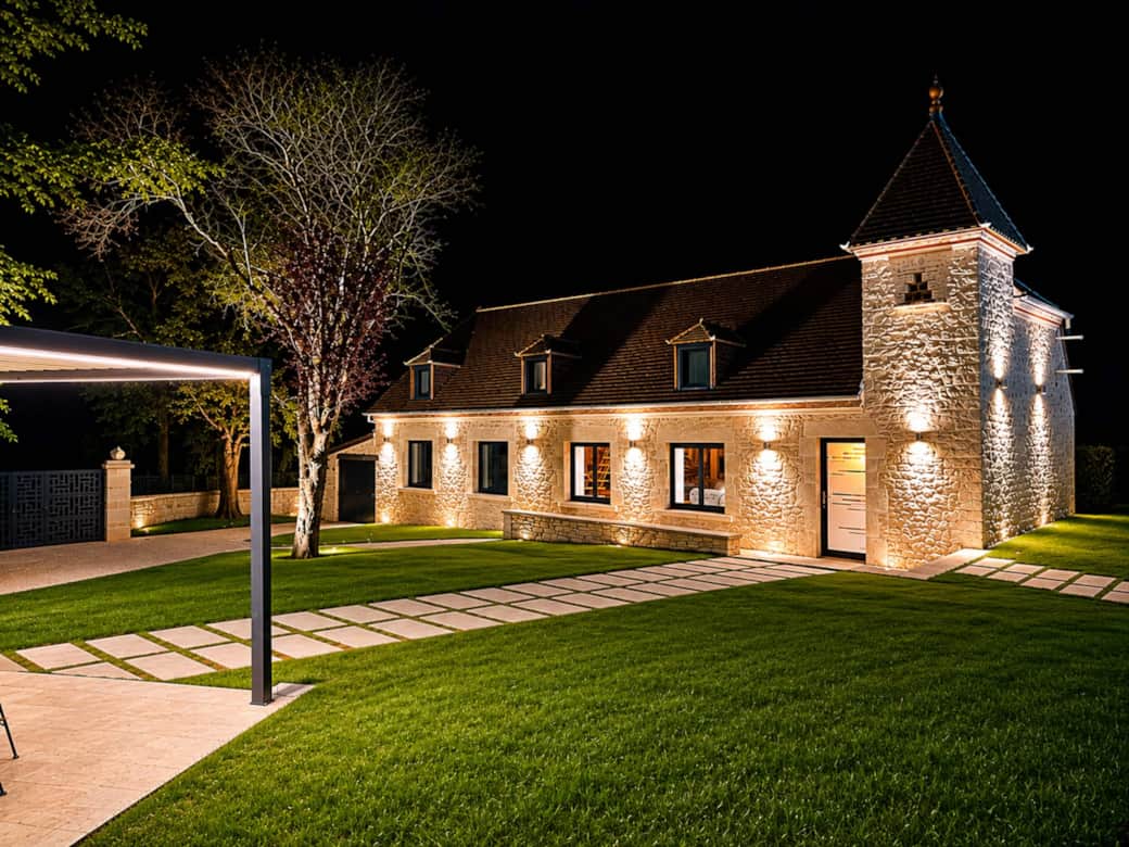 La façade de pierre de la Bastide du Causse, mise en lumière le soir
