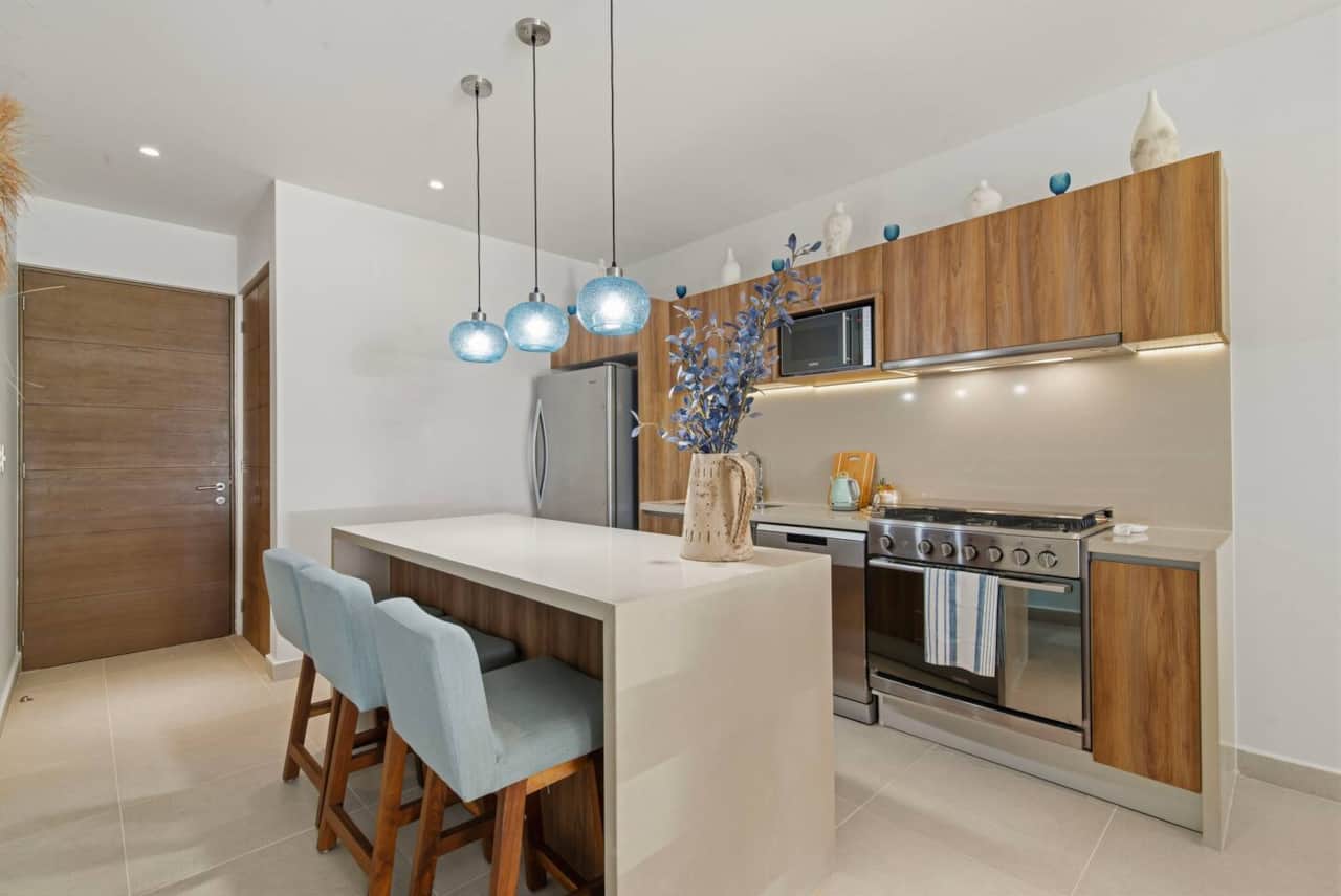 The kitchen features a six-burner stove and oven, refrigerator, dishwasher, microwave, toaster, blender, and coffee maker. Coffee, cookware, dishes, utensils, spices, and filtered drinking water are provided, plus island seating for three.