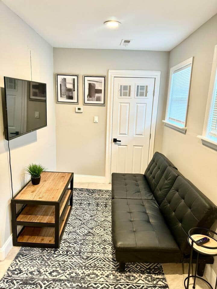 The living room boasts a spacious layout, complete with a large flatscreen TV equipped with Roku channels, and a comfortable futon sofa.
