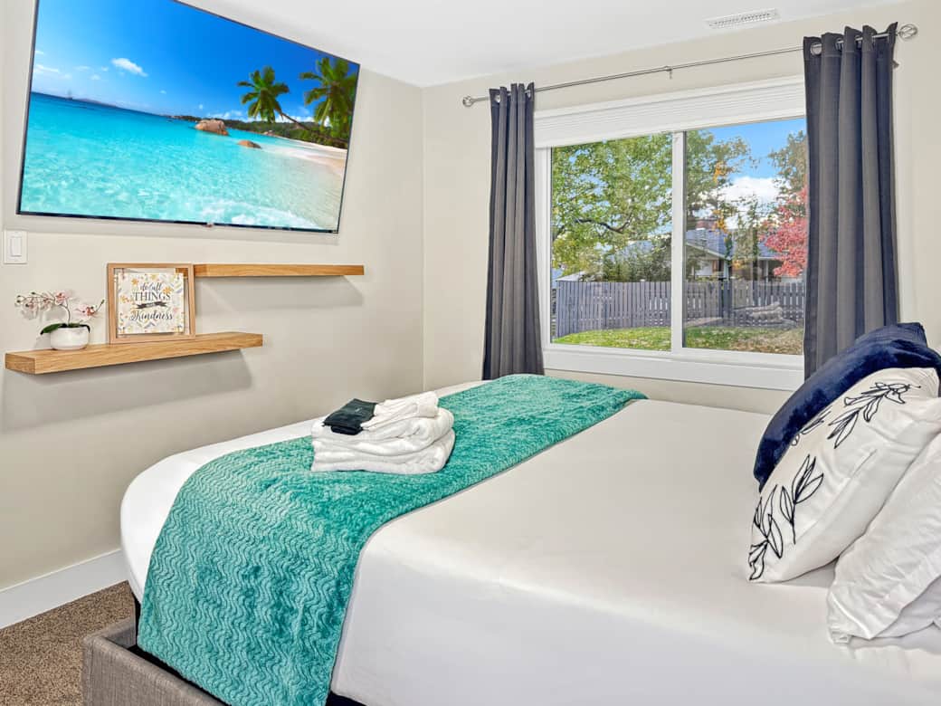 Bright Bedroom with Large Window and Smart TV