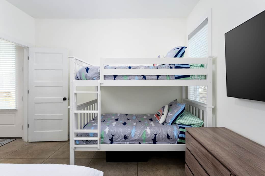 First-floor private suite with queen bed, bunk beds, Smart TV, and full bath.