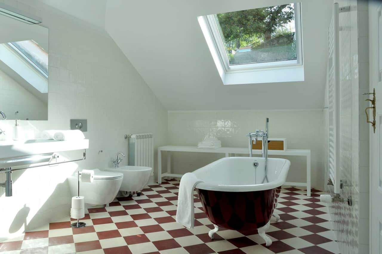 Baño abuhardillado con bañera exenta y suelo ajedrezado