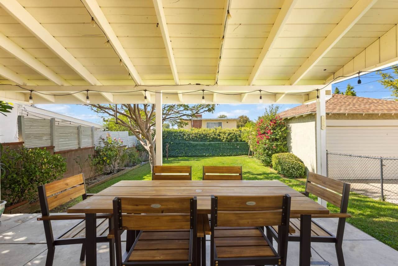 A large wooden dining table under the patio is ideal for warm evening gatherings.
