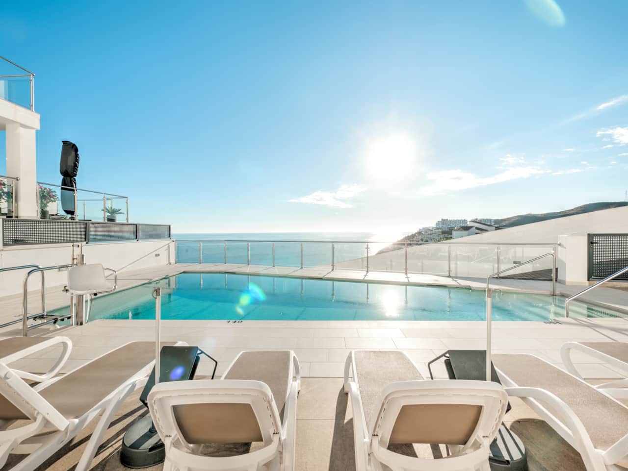 Communal swimming pool with stunning sea views and sun loungers.