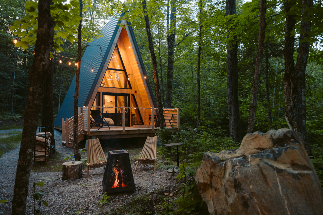Le chalet qui s’illumine au crépuscule, au cœur de la forêt. Crédit phote: @rollingvan