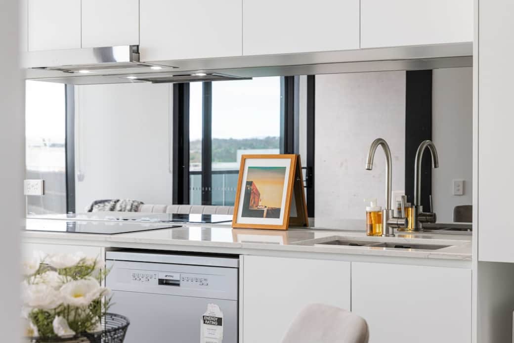 This bright kitchen is a chef's delight, featuring a large window that lets in ample natural light. The stainless steel sink and modern appliances make cooking a breeze. The white countertops and backsplash add to the room's fresh and airy feel.