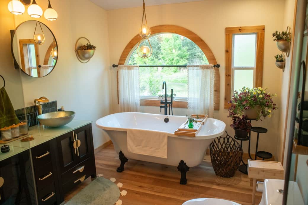 The en suite bath offers elegant vessel sinks, a rain shower, and a clawfoot soaking tub with a picturesque view,. It’s thoughtfully stocked with towels, shampoo, soap, organic tampons, flossers, eco toothbrushes, and more for your comfort and care.