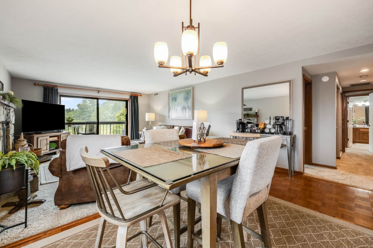 Dining table looks toward the living room, fireplace, and large balcony.  
