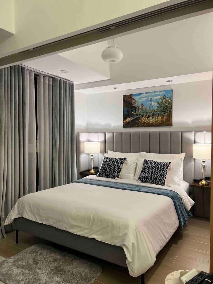 The bedroom is equipped with a queen-size bed, a comfortable duvet and pillows, and blackout curtains.