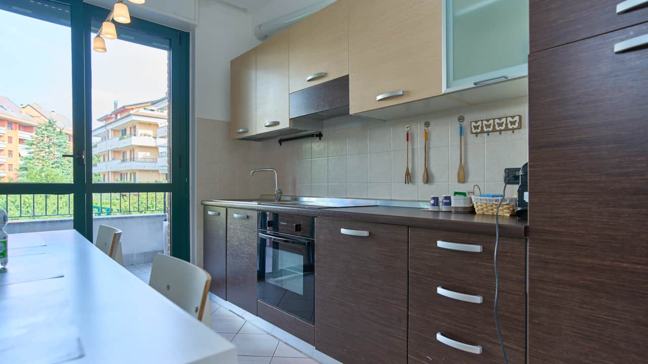 Cocina con muebles oscuros, horno y ventana al verde