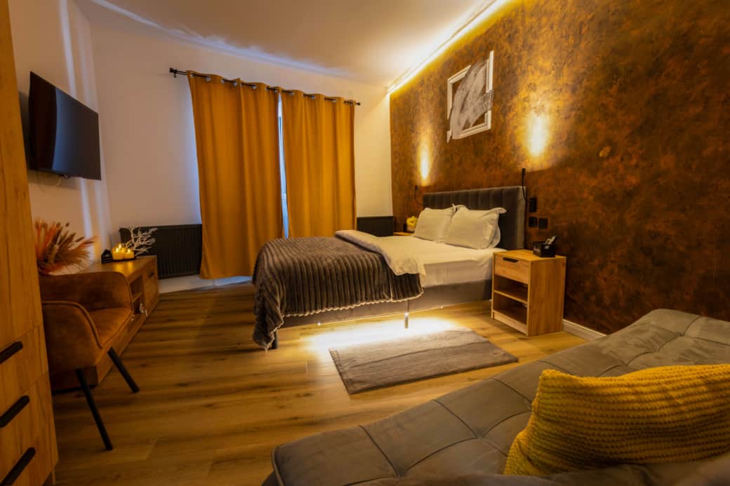 Spacious bedroom with queen bed, smart TV, velvet armchair, sofa, LED mood lights