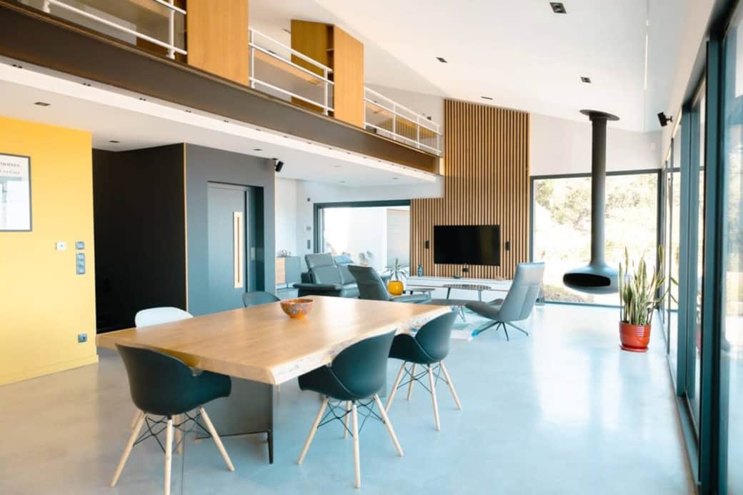 Une grande table en bois massif trône au cœur de l’espace à vivre. Conviviale et fonctionnelle, elle est idéale pour des repas en famille ou entre amis, avec une vue mer en toile de fond.