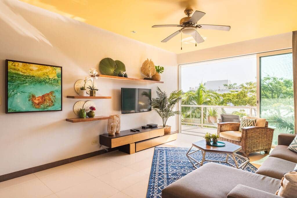 The sun-filled living room opens onto a private balcony overlooking the pool and lush landscaping