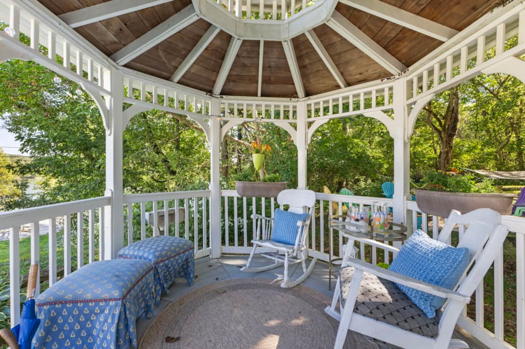 Rocking chairs and ottomans in the Gazebo with relaxing views of the river & water fountain feature.