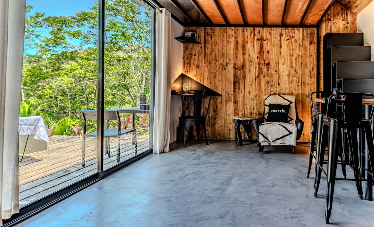 Living space framed by forest views through the sliding doors of our eco cabin, Valle de Antón