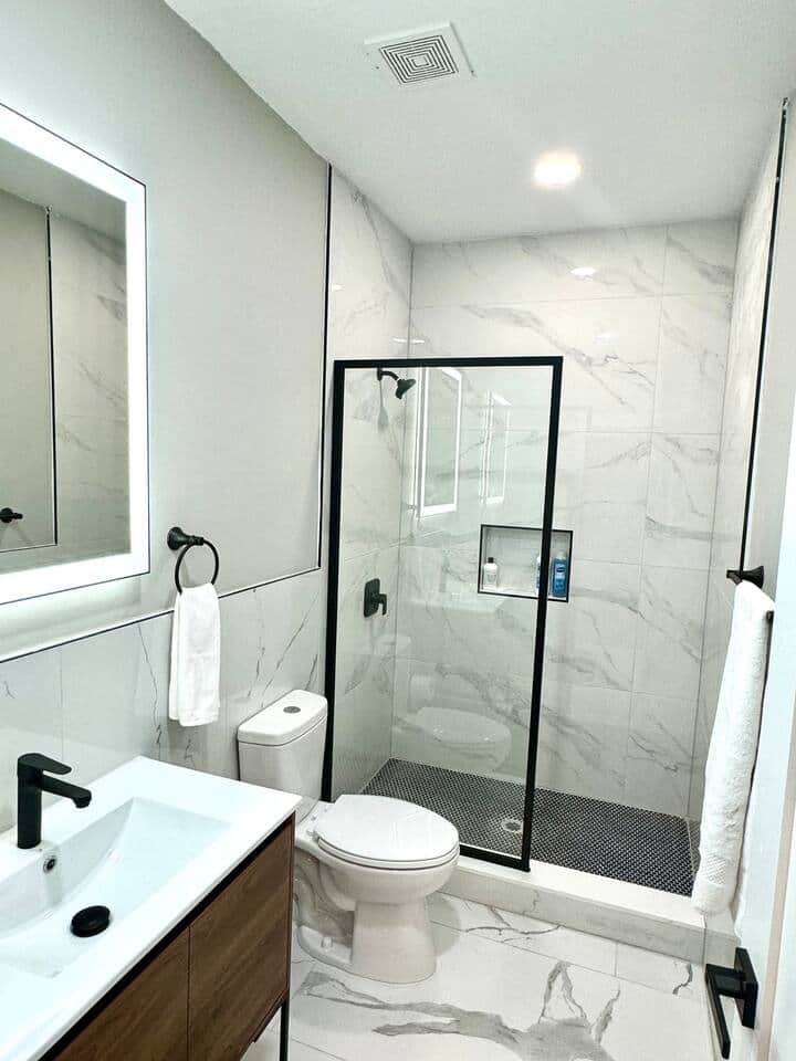 This beautiful bathroom, featuring elegant Carrara tile on both the shower and floor. The lit mirror adds a touch of sophistication and makes getting ready a breeze. You'll love the serene atmosphere and stylish design perfect for a relaxing retreat.