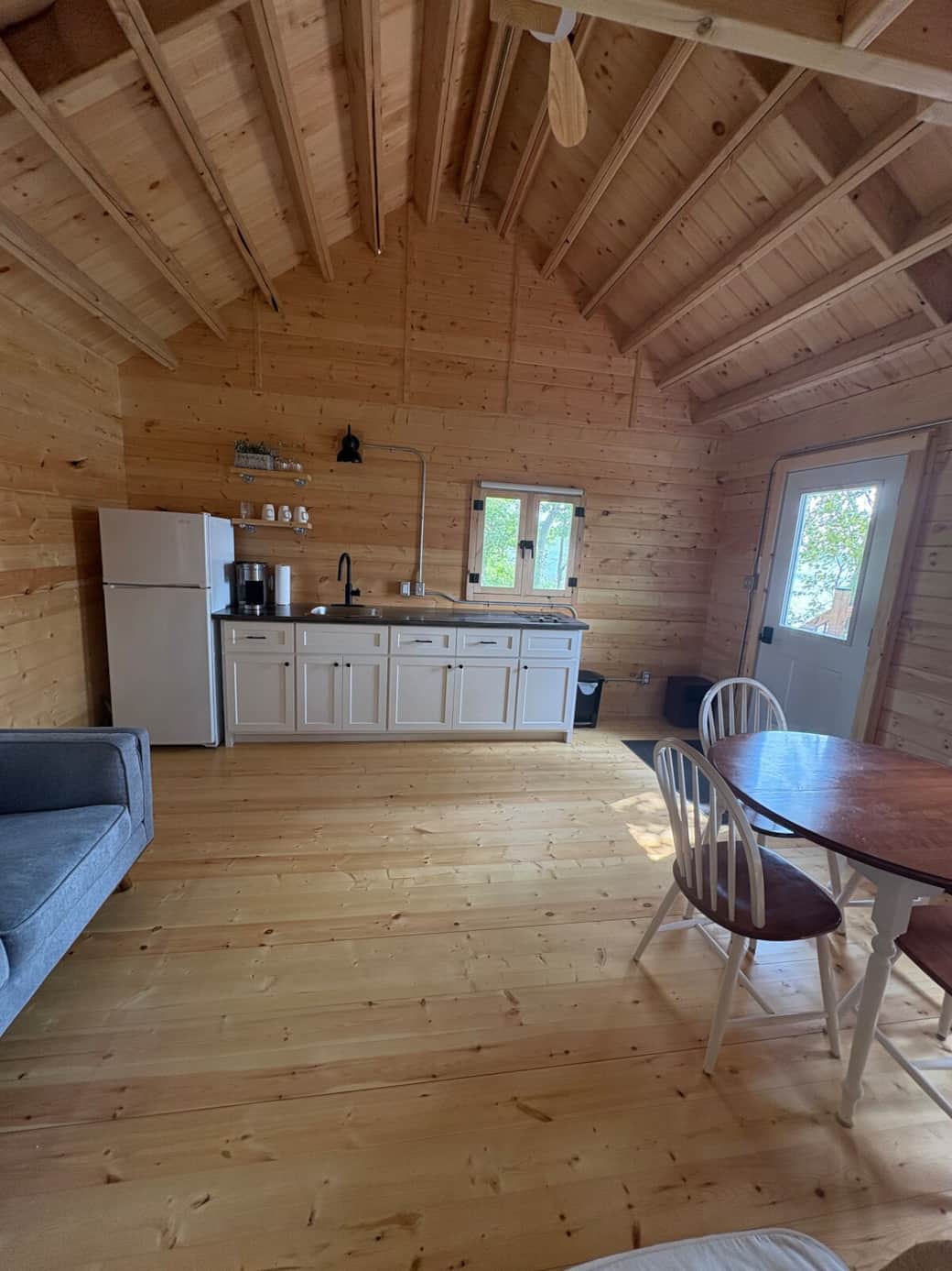 Kitchen with fridge/freezer, keurig machine, water kettle, 2 pit stove and cups, glasses, plates, cutlery, pots, pans, knives etc.