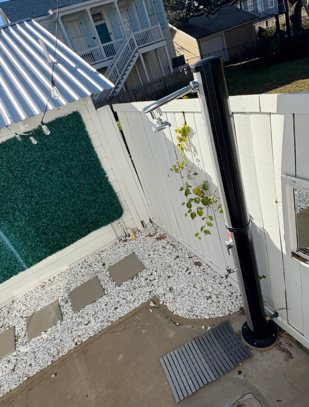 Modern outdoor shower at White Magnolia Galveston surrounded by greenery