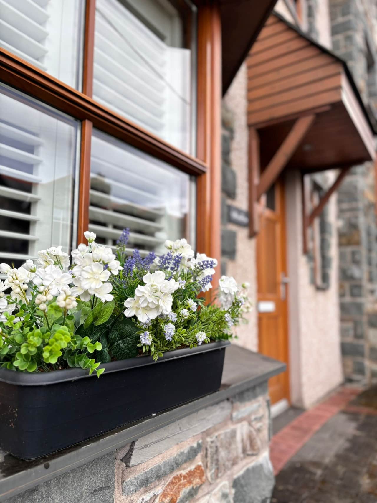 Charming entrance with vibrant window box flowers. 
