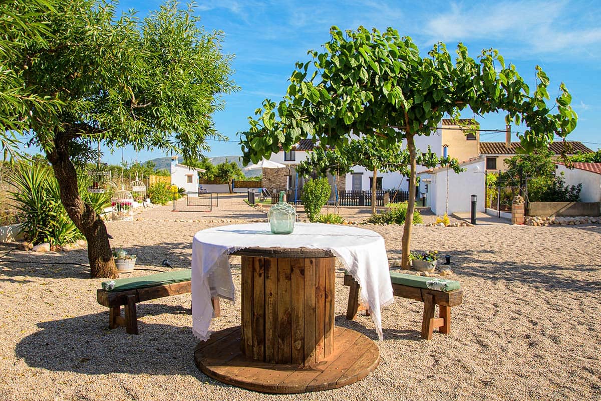 Rincón rústico con mesa de bobina de madera y vistas al exterior | Masía de Cholito