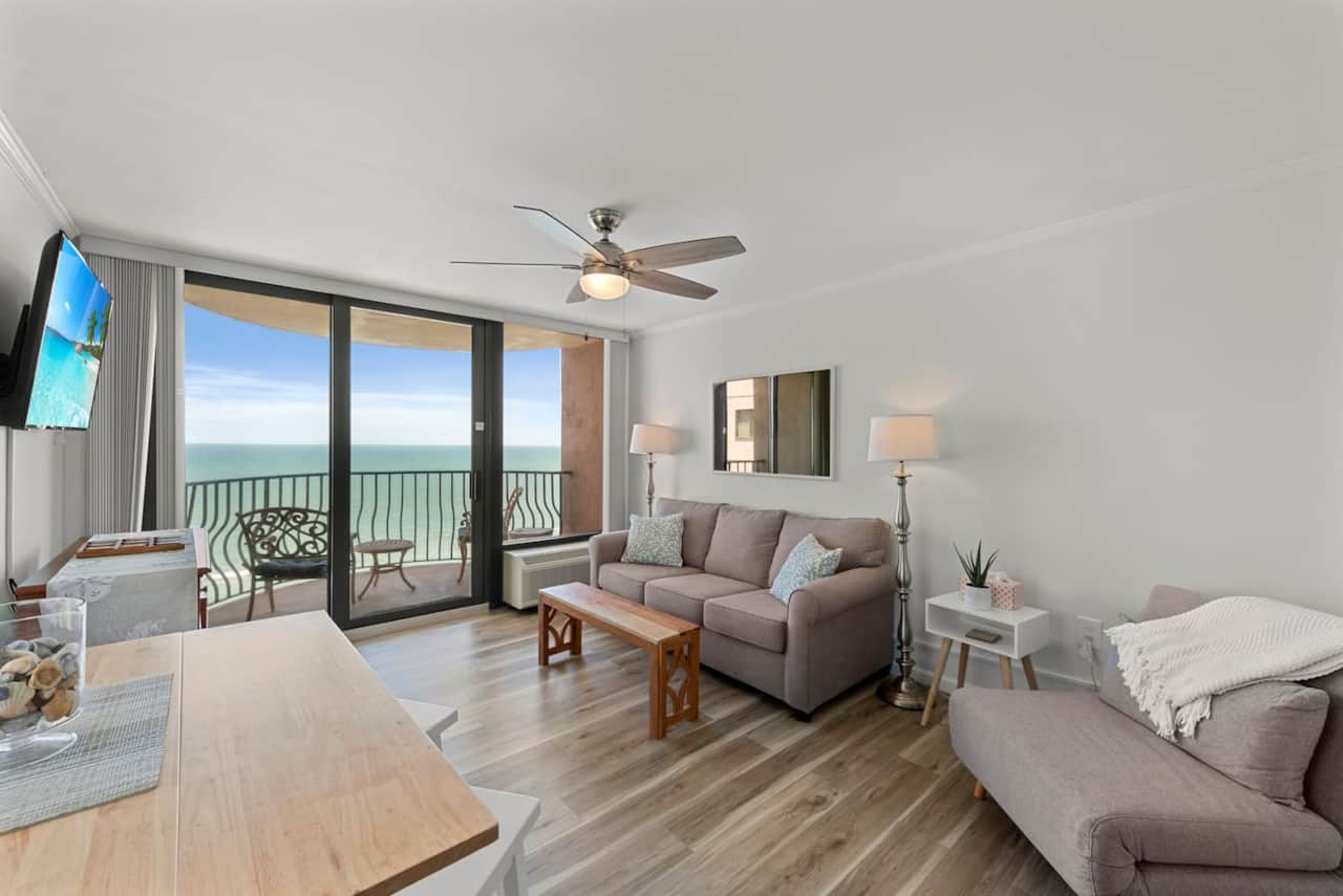 Stunning oceanfront living room with floor-to-ceiling glass doors, private balcony seating, and a cozy coastal lounge setup — the perfect spot to unwind with a view. ☀️
