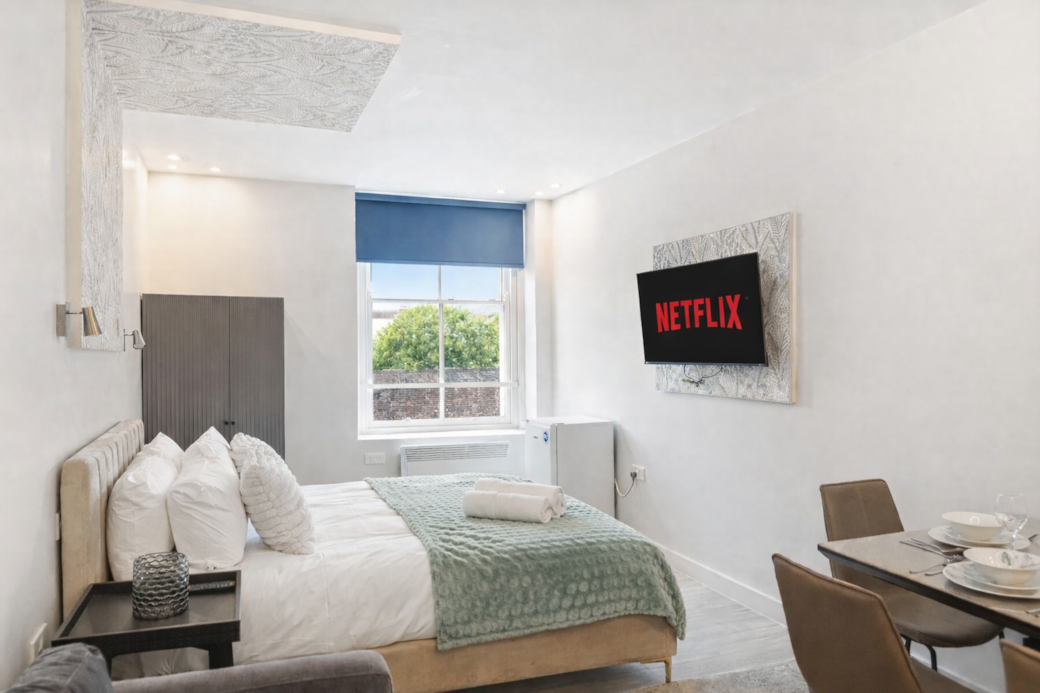 Bright and stylish bedroom featuring a plush double bed with luxury linens, feature wallpaper Bright and stylish bedroom featuring a plush double bed with luxury linens, feature wallpaper