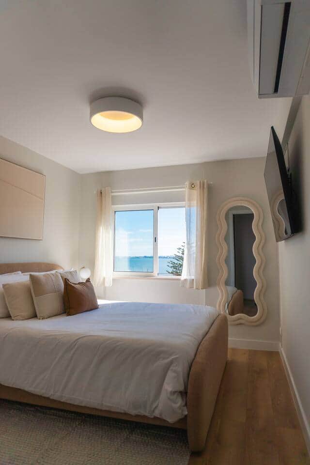 Wake up to this!  A mobile friendly view showing the bed, water view, wall-mounted TV, and the all-important AC unit.