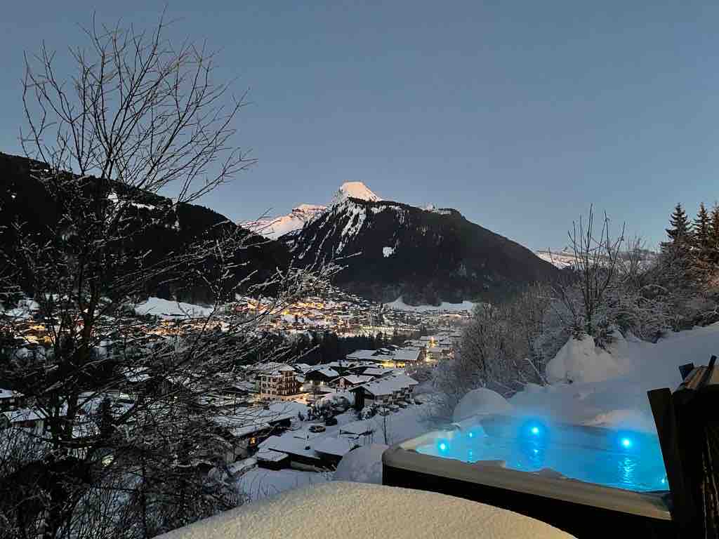 Jacuzzi du chalet face à la vallée de Morzine enneigée, de nuit