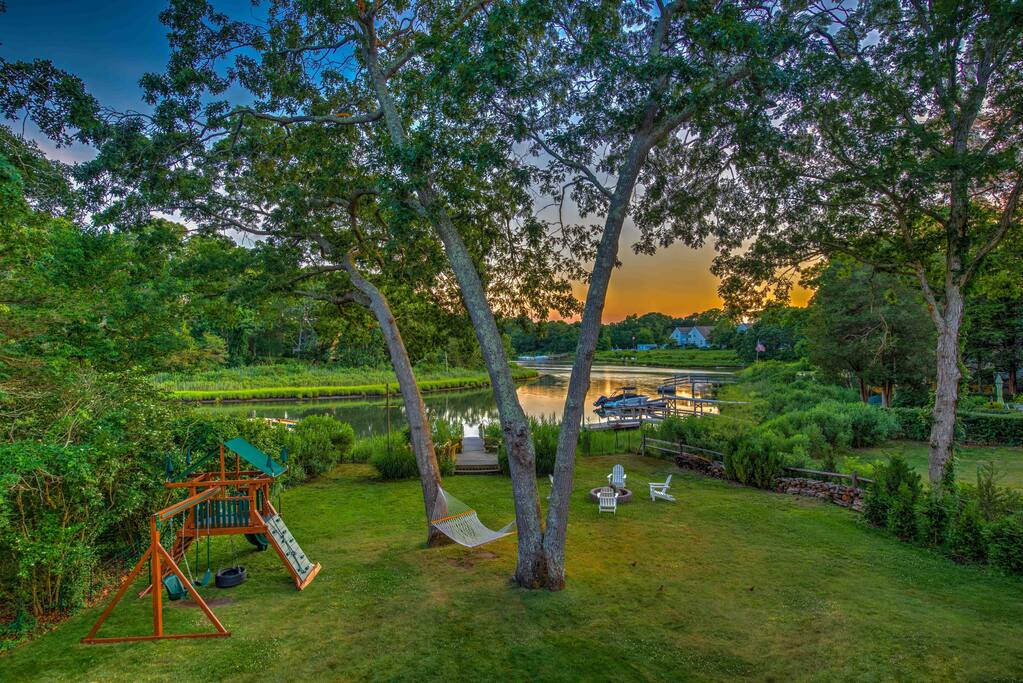Sunset over the cove from the back lawn, with the playset, hammock and fire pit