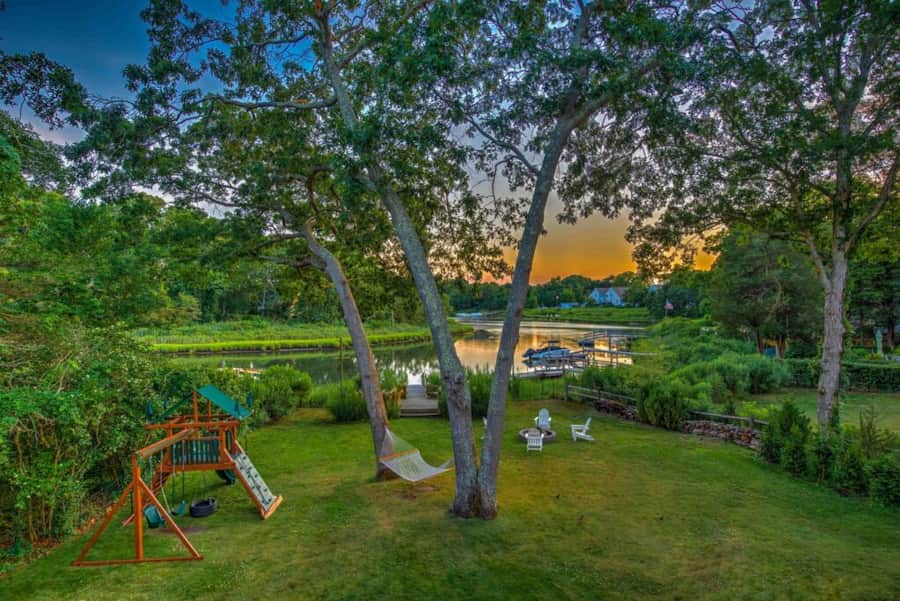 Sunset over the cove from the back lawn, with the playset, hammock and fire pit