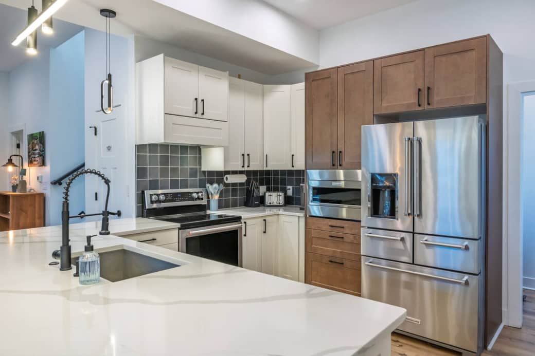 Modern, sleek well-stocked kitchen with white quartz countertops, range with convection oven, microwave, dishwasher, and full-size fridge for a seamless dining experience.