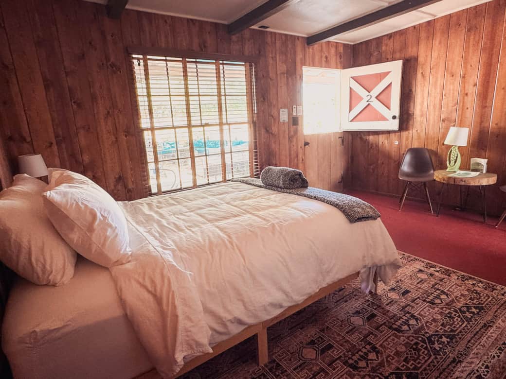 Queen bed with window view, vintage Dutch door and seating area.