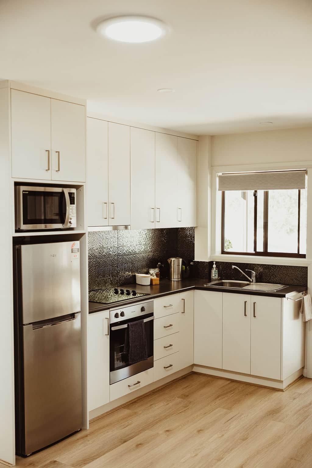 Equipped kitchen with fridge, cooktop, oven, crockery and cutlery