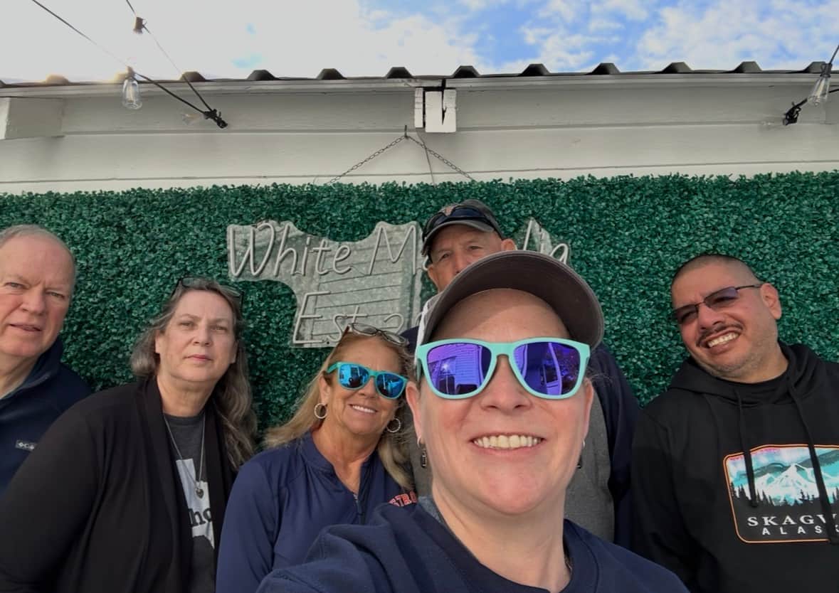 Family selfie in front of the White Magnolia Galveston courtyard photo wall before their cruise