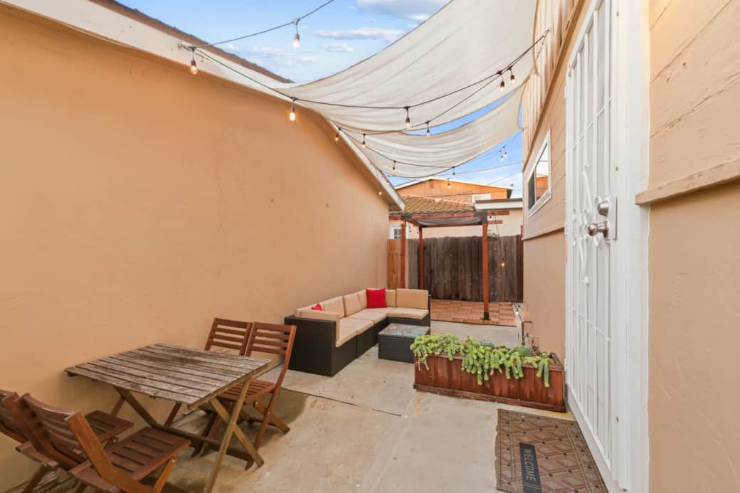 Charming private patio with dining table, cozy lounge seating, and string lights 