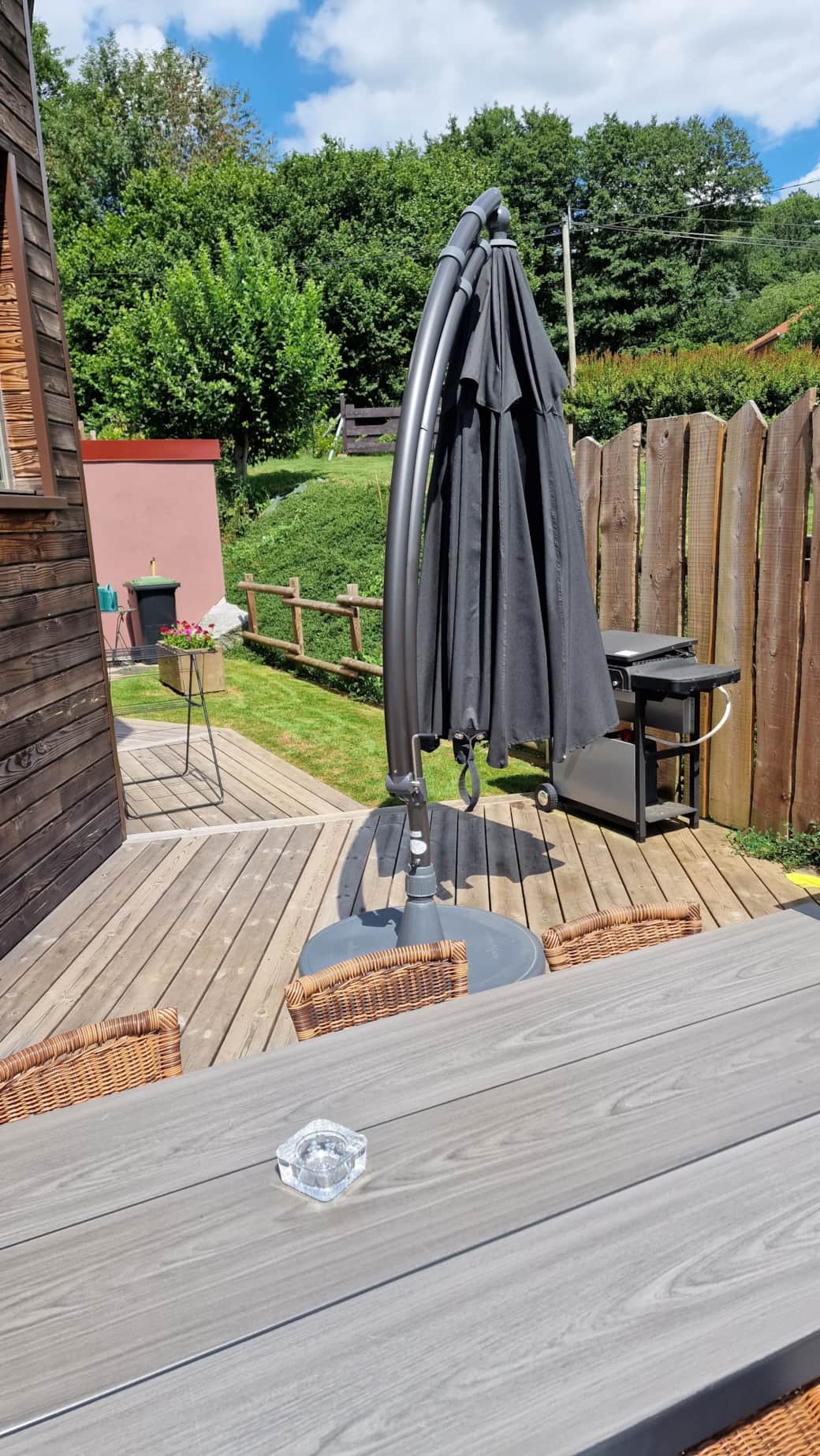 Vue de la terrasse avec parasol, barbecue et table