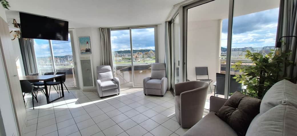 Salon avec 3 grandes baies vitrées dont l'une avec un balcon couvert