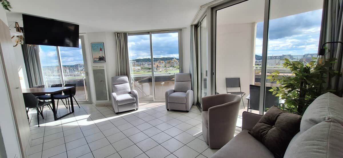 Salon avec 3 grandes baies vitrées dont l'une avec un balcon couvert