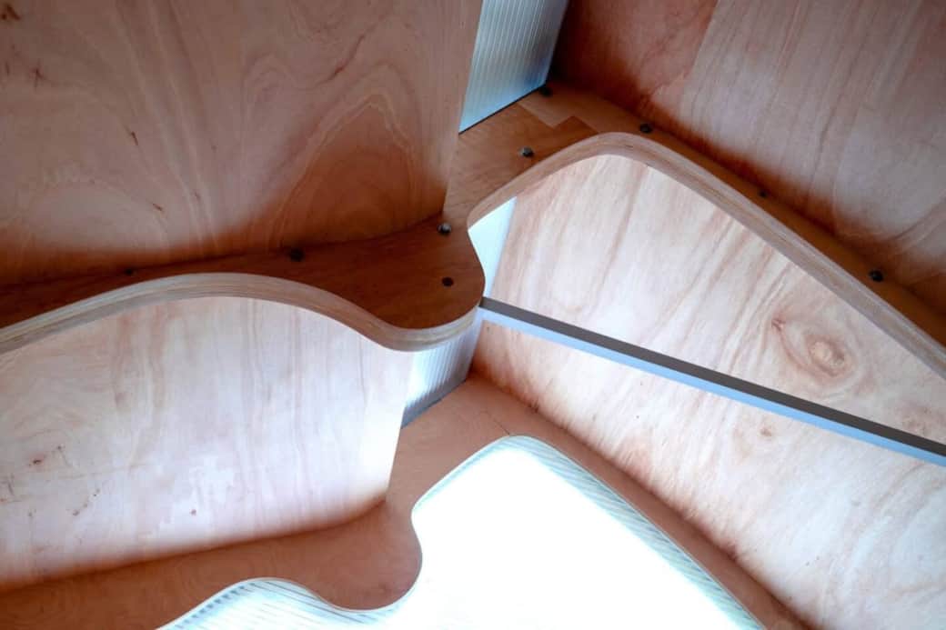 Looking up from the bed at the laminated plywood ribs — the cabin's monocoque structure exposed.