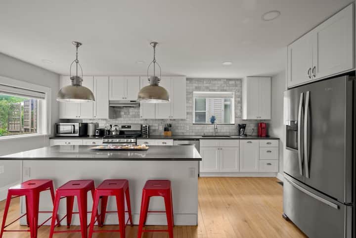 Bright, modern kitchen with stainless steel appliances, spacious island seating, and stylish pendant