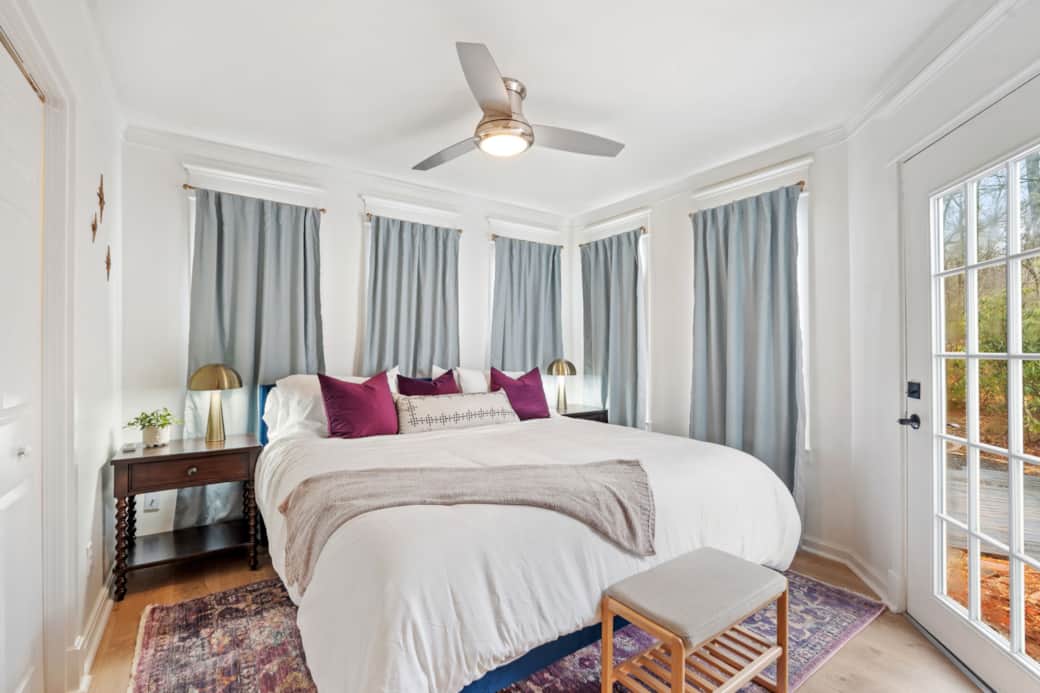 Bright, cozy bedroom with king bed, plush linens, and private exterior access to bridge and fire pit