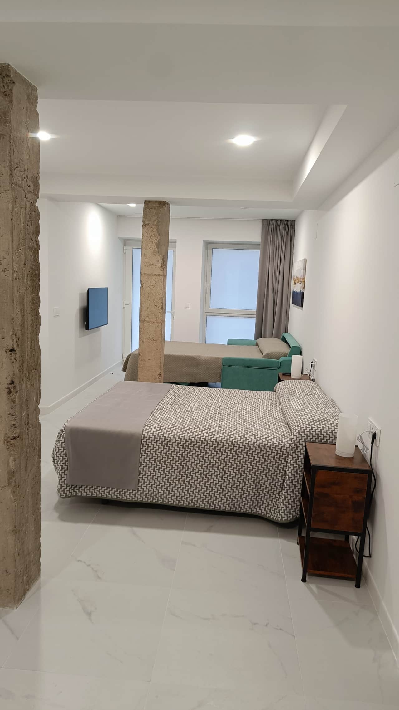 Dormitorio con sofá cama abierto y doble columna decorativa