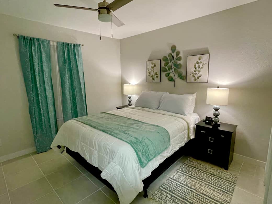 Queen size bedroom with two night stands and lamps. There is a phone charger clock on the right side